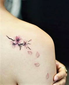 a woman's back with pink flowers on her left shoulder and the upper half of her arm