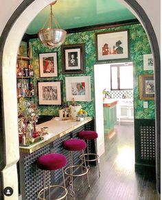 a bar with stools and pictures on the wall behind it in a room that has green walls