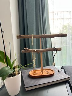 a wooden balance scale sitting on top of a table next to a potted plant