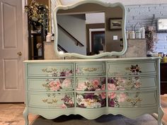 an ornate dresser with flowers painted on it and a large mirror over the top, in front of a doorway