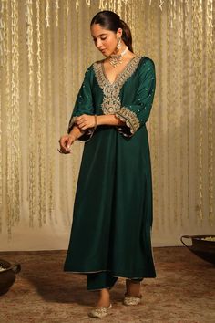 Emerald green long kaftan with placed thread embroidered paisley motifs embellished by sequins. Comes with matching doghri salwar.
Components: 2
Pattern: Embroidered
Type Of Work: Thread, Sequin
Neckline: V-neck
Sleeve Type: Three quarter
Fabric: Silk Dupion
Color: Emerald Green
Other Details: 
Flared silhouette
Occasion: Sangeet,Mehendi and Haldi - Aza Fashions Traditional V-neck Festive Dress, Eid Anarkali V-neck Dress, V-neck Dress With Intricate Embroidery For Eid, Green Wedding Kaftan For Eid, Semi-stitched V-neck Dress For Festive Occasions, Semi-stitched V-neck Festive Dress, V-neck Traditional Wear For Eid, Green V-neck Kaftan For Eid, Bohemian V-neck Sets With Resham Embroidery