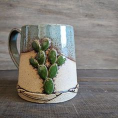 a ceramic mug with a small green cactus on the inside, sitting on a wooden table