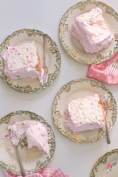 four pieces of cake on plates with pink frosting and sprinkles around them