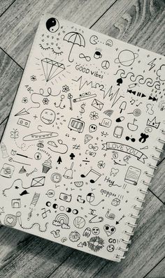 a notebook with doodles on it sitting on top of a wooden floor