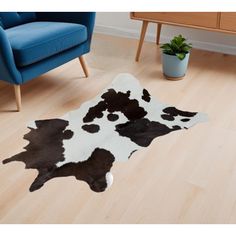 a black and white cowhide rug on the floor in a living room next to a blue chair