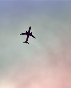 an airplane is flying in the sky on a cloudy day with pink and blue clouds