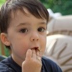 a young boy eating something with his hands