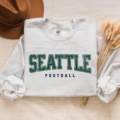 Get ready for game day with this cozy Seahawks football crewneck! Perfect for Seattle football tailgating, gifting, or showing off your football pride. 🎉 This unisex sweatshirt is the ultimate fan gift for him, her, or anyone who loves Seattle football. Hello there! 😊👋 If you're on the hunt for some seriously cozy sweatshirts, you've come to the right place! I'm absolutely passionate about what I do, and my mission is to make your shopping experience absolutely perfect. If you ever have any q Team Spirit T-shirt For Game Day In Winter, Winter Game Day Varsity T-shirt, Winter Game Day T-shirt With School Spirit Style, Varsity T-shirt For Game Day In Winter, School Spirit T-shirt For Game Day In Winter, Seahawks Game Day, Football Crewneck, Game Day Sweatshirt, Seahawks Fans