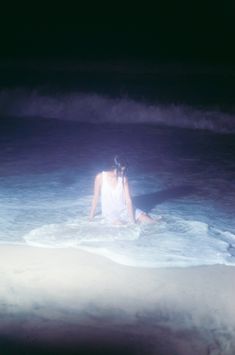 a woman sitting in the ocean at night