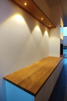 an empty kitchen with wooden counter tops and lights on the wall above it, along with blue tile flooring