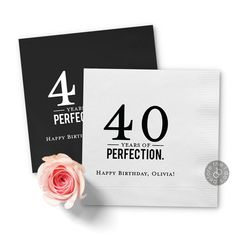 a black and white greeting card with a pink rose on it next to a napkin that says 40 year of perfectionion