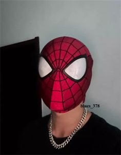 a man wearing a spiderman mask with chains on his neck