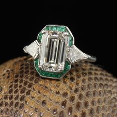 an emerald and diamond ring sitting on top of a ball