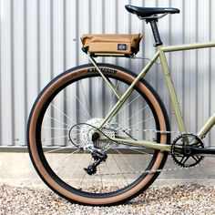 a green bike parked in front of a building with a brown bag on it's back tire