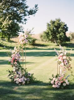 an outdoor ceremony setup with flowers and greenery on the grass in front of trees