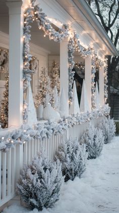 the front porch is covered in snow and decorated with christmas lights, garlands and trees