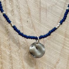 Made with navy blue glass Czech seed beads and Japanese Miyuki Delica galvanized silver beads on strong elastic cording with a tarnished silver metal coin charm. The stretchy Boho beaded necklaces go right over the head, without the hassle of a clasp. Embracing the beauty of simplicity, our seed bead necklaces feature subtle silver or gold-colored pendants inspired by the tranquility of the natural world. Each pendant is carefully chosen to complement the seed bead colors and enhance the necklace's aesthetic appeal. Can be made in custom colors. Adjustable Silver Beaded Necklace With Polished Beads, Adjustable Silver Metal Bead Necklaces, Silver Adjustable Beaded Necklace With Polished Beads, Adjustable Silver Metal Beaded Necklaces, Adjustable Round Sterling Silver Beaded Necklaces, Silver Beaded Necklace With Polished Round Pendant, Silver Nickel-free Beaded Necklaces, Adjustable Silver Beads Round Necklaces, Adjustable Round Necklace With Silver Beads