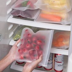 a person reaching into an open refrigerator door with food in plastic containers on the shelves