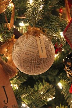 an ornament hanging from a christmas tree with ornaments around it and the word joy written on it