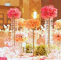 the table is set with pink flowers and crystal vases for centerpieces on each side