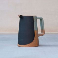 a brown and black pitcher sitting on top of a table