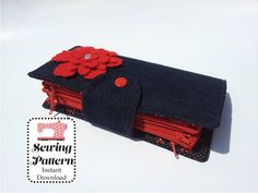 a wallet with red flowers on it sitting on a white surface, next to a pair of scissors