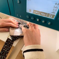 a person is using a machine to sew on a leopard print neck tie in front of a computer screen