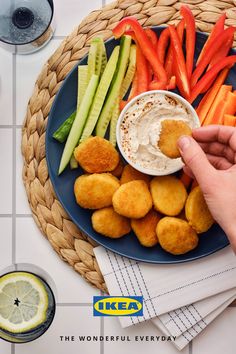 a person dipping dip into some food on top of a blue plate with carrots and celery