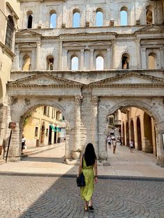 a woman in a yellow dress is walking through an old stone building with arched doorways