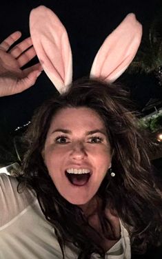 a woman with bunny ears on her head is making a funny face at the camera