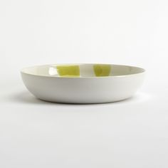 a white bowl with green stripes on the rim is shown in front of a white background