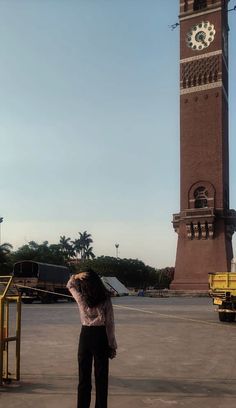 a woman standing in front of a tall clock tower