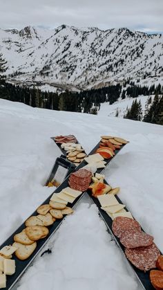 a cross made out of crackers and cheeses in the snow with mountains in the background