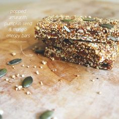 two granola bars sitting on top of a wooden cutting board with seeds scattered around them