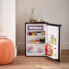 an open refrigerator sitting on top of a hard wood floor