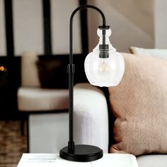 a table lamp sitting on top of a wooden table next to a white couch in a living room