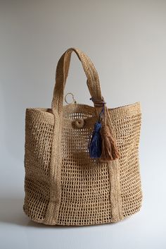 a straw bag with a blue tassel hanging from it's handle and handles