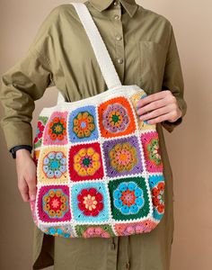 a woman holding a multicolored crocheted bag