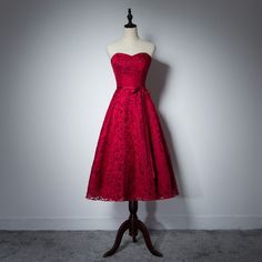 a red dress on a mannequin stand in front of a white wall and grey carpet