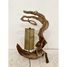 a piece of driftwood with a lamp on it sitting on a wooden floor next to a white wall