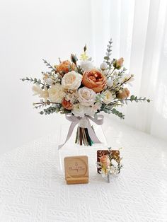 a bouquet of flowers in a glass vase next to a small wooden box with a photo on it