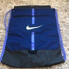 a blue and black nike gym bag on the floor with a white nike logo on it