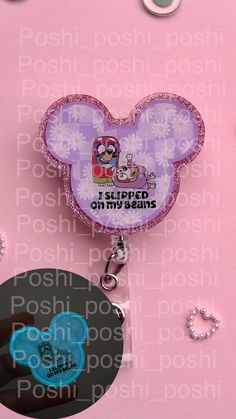 a mickey mouse keychain is shown on a pink background with other items around it