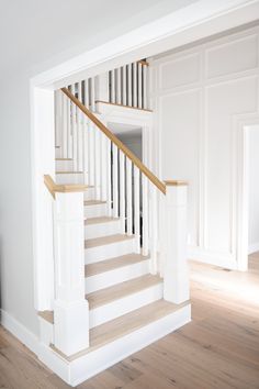 a white staircase with wooden handrails in a house