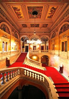 an ornate building with red carpeted stairs and chandeliers