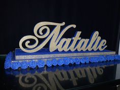 a blue and white sign that says natlle on it's side, with roses in the foreground