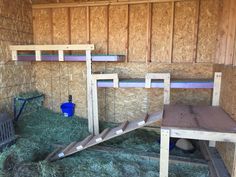 the inside of a barn with hay and ladders on it's sides, next to a blue bucket