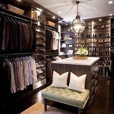 a walk - in closet with lots of clothes on shelves and a bench next to it