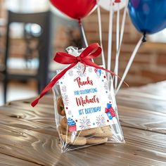 there is a bag with cookies in it on the table and some balloons behind it