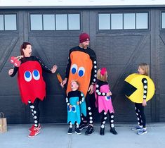 three adults and two children in costumes standing next to a garage door with doors open